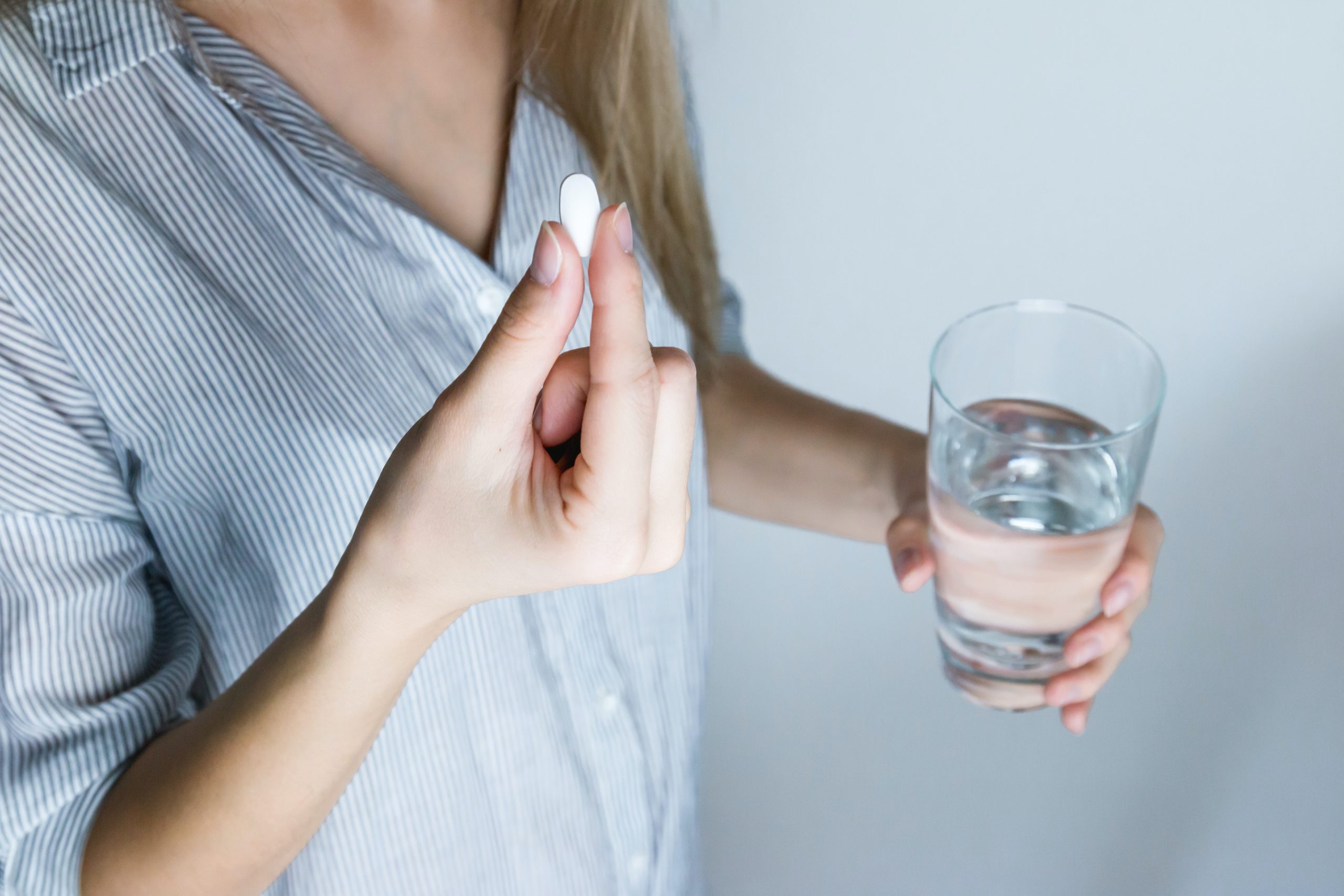 Disbiosi - Signora che tiene un bicchiere d'acqua e un probiotico